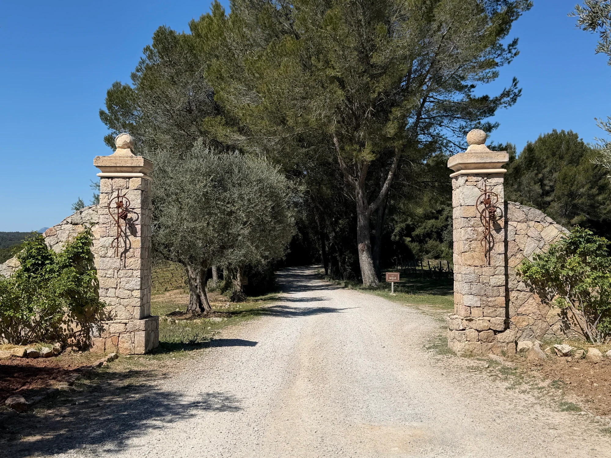 The entrance to Château Rasque between stone pillars and trees